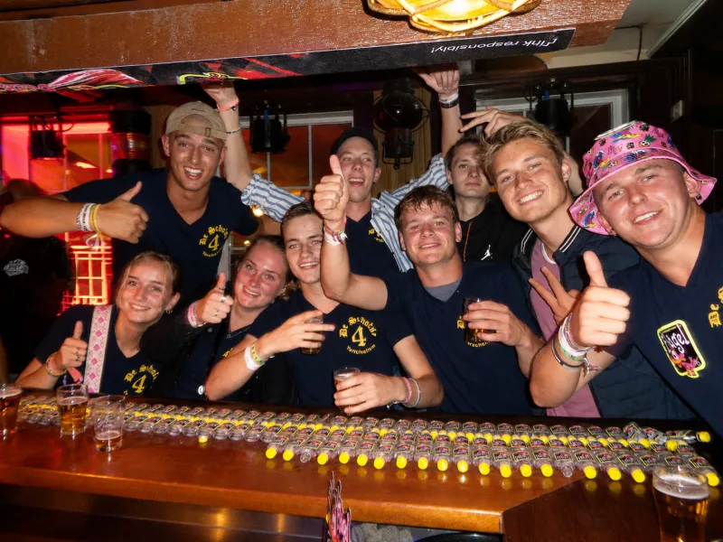 Vrienden in De Schotse 4-polo's achter de bar, met een rij shotjes klaargezet
